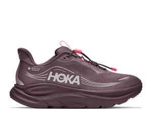 A Hoka running shoe in a muted plum-brown colorway, featuring a textured mesh upper, a thick cushioned sole, and bright pink laces