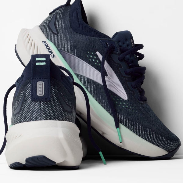 Navy and white running shoes with visible 'Brooks' branding on a light gray background