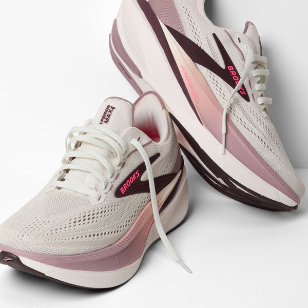Pair of white and pink running shoes with 'Brooks' branding on a light background
