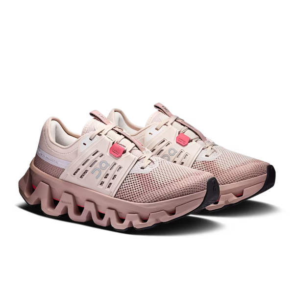 A pair of mesh athletic sneakers in a light blush pink and beige colorway, featuring a chunky wavy sole and small bright pink accents on the laces, shown against a plain white background.