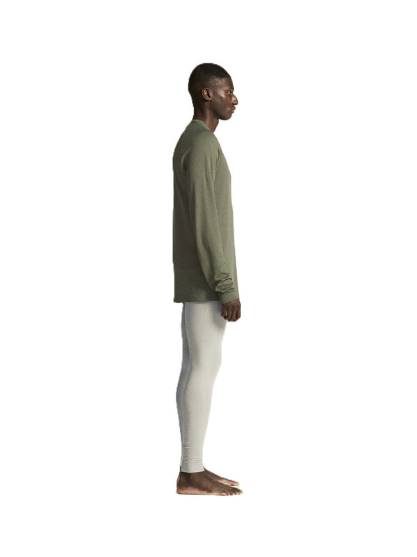 Person wearing a green long-sleeve shirt and white pants on a white background