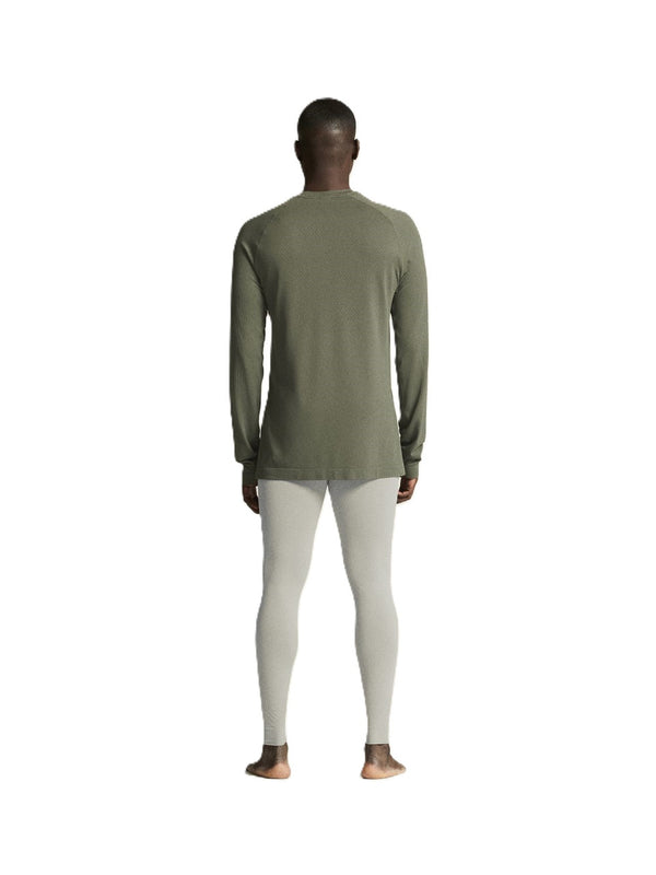 Person wearing a green long-sleeve shirt and white leggings on a white background