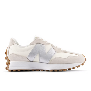 A New Balance low-top sneaker in off-white and beige suede with a metallic silver 'N' logo, a white midsole, and a brown gum outsole, shown in a side profile on a white background.