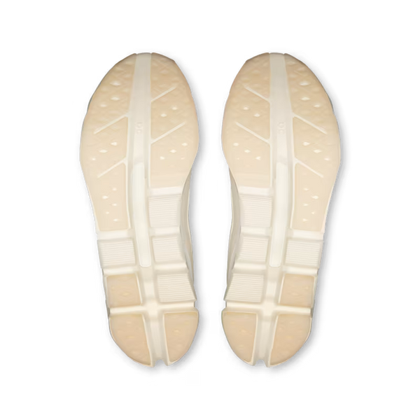 Top-down view of a pair of off-white athletic shoes showing the textured outsoles against a solid white background.