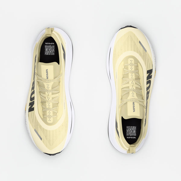 Pair of light yellow sneakers with black accents on a white background