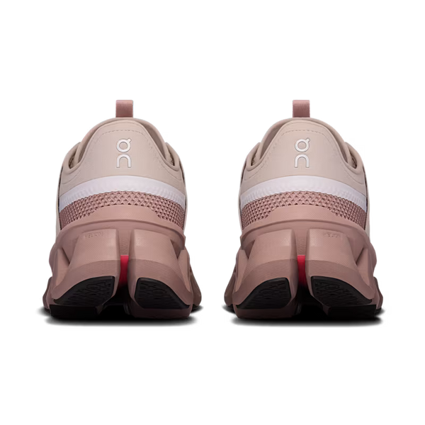 A pair of running shoes shown from the back, featuring a dusty rose and white colorway with a distinctive chunky sole and the 'on' logo on the heel.