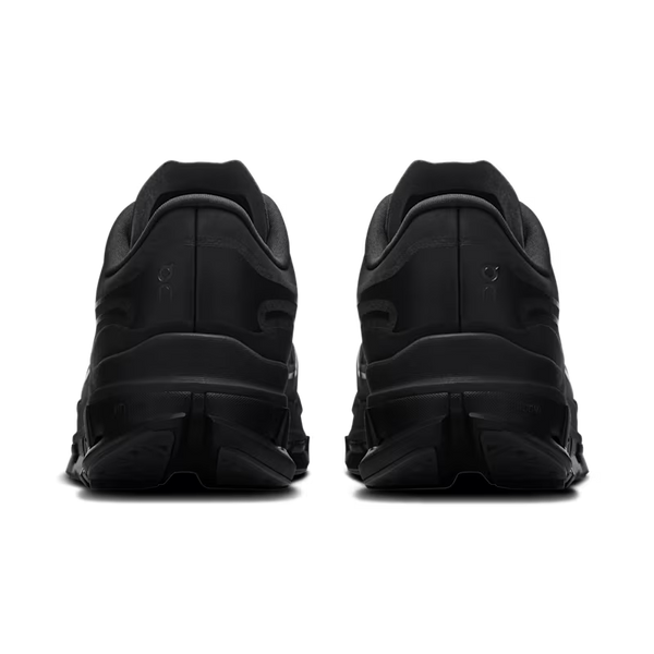 A pair of black chunky sneakers shown from the back, featuring thick layered soles and a monochromatic design, set against a plain white background.