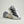 White Adidas sneaker with black stripes on a light gray background