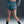 Person wearing blue athletic shorts on a dark background