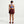 Person wearing a blue sports bra and maroon skirt on a white background