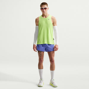Man wearing a bright green sleeveless shirt and purple shorts on a white background