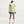 Person wearing a bright green sleeveless shirt and blue shorts on a white background