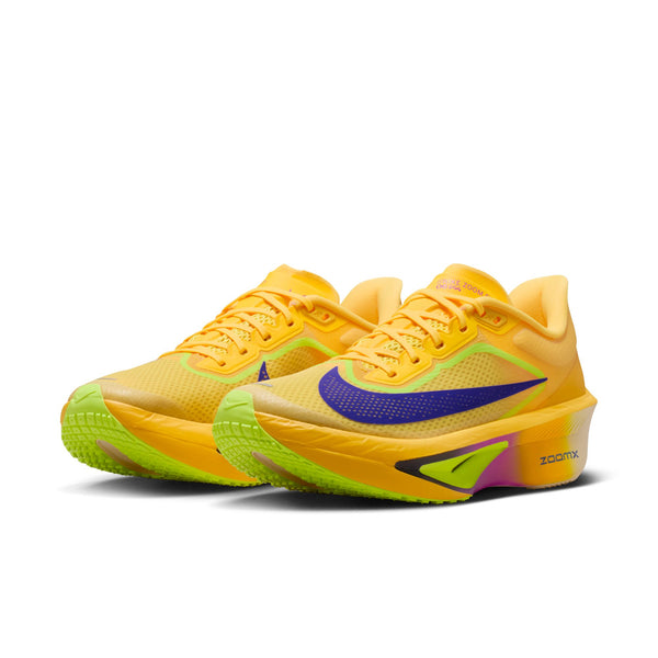 Yellow womens Nike ning shoes with a purple swoosh logo on a white background.