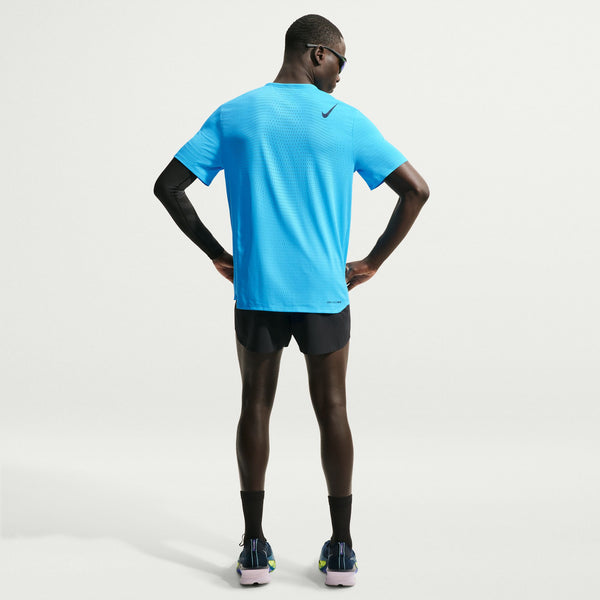 Person wearing a blue athletic shirt and black shorts on a light gray background