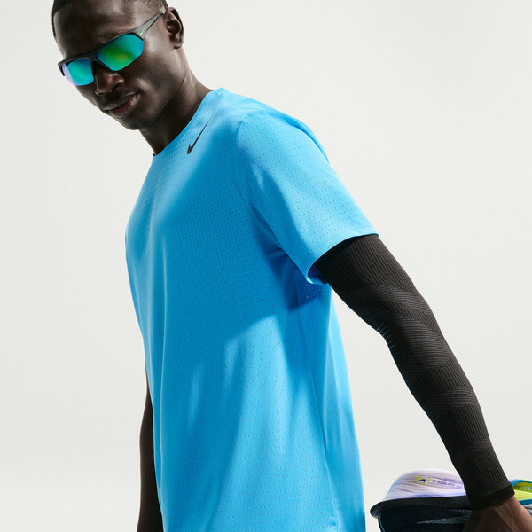 Person wearing a blue athletic shirt and black arm sleeve on a light gray background