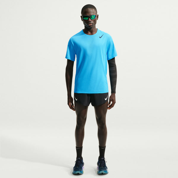 Person wearing a blue athletic shirt and black shorts with Nike logo on a white background