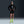 A model wearing a black Nike running jacket, black running shorts, neon yellow socks, and neon yellow running shoes, posing against a dark gray studio background.