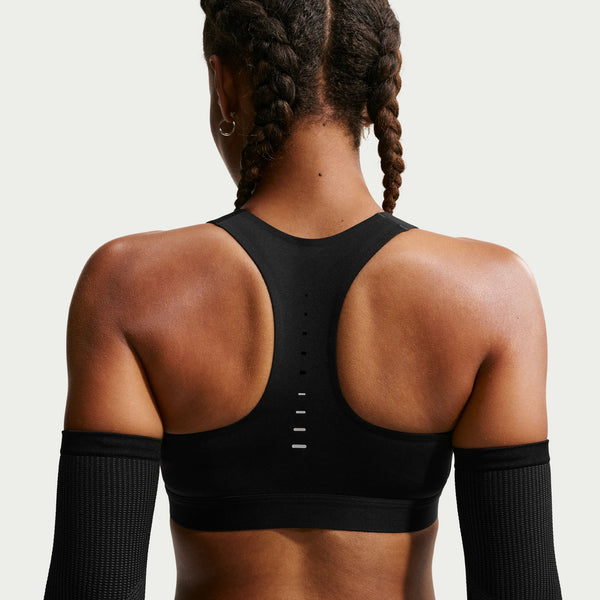 Person wearing a black sports bra with open back design on a plain background