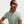 Person wearing a light green Nike t-shirt and sunglasses on a plain background