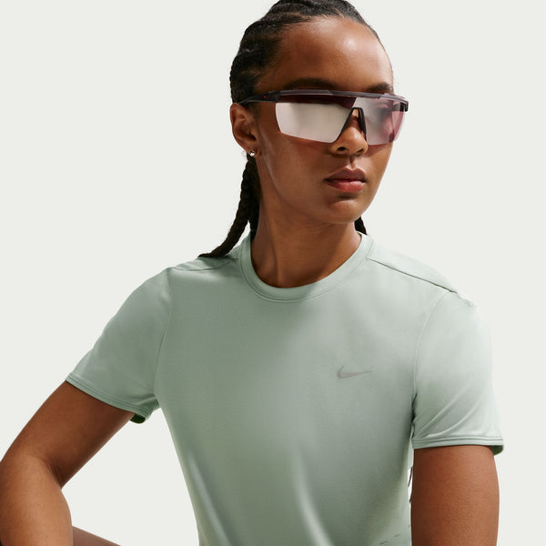Person wearing a light green Nike t-shirt and sunglasses on a plain background