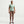 Person wearing a light green t-shirt and brown leggings on a white background