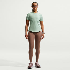 Person wearing a light green t-shirt and brown leggings on a white background