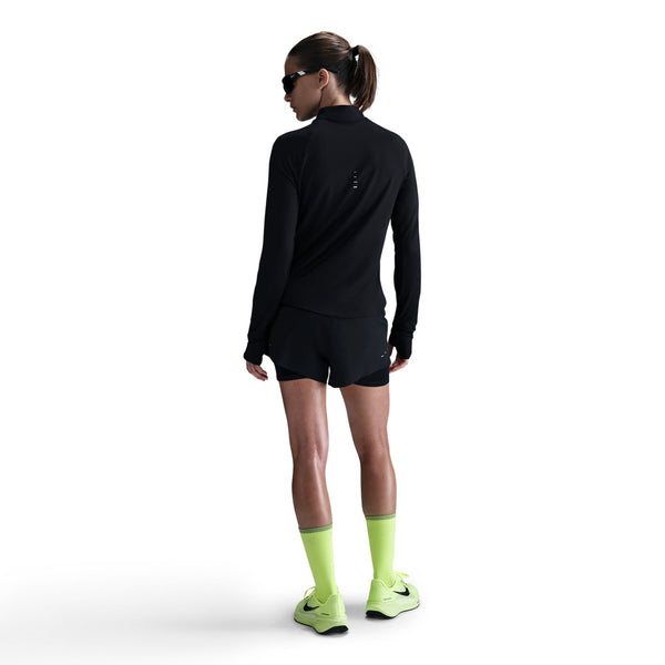 Person wearing a black athletic outfit with neon green socks and shoes on a white background