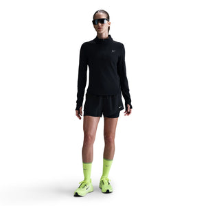 Person wearing a black athletic outfit with neon green socks and shoes on a white background