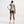 Person wearing a light green tank top and dark shorts on a white background