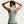Woman wearing a light green tank top with a plain background