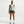 Woman wearing a light green sleeveless top and purple shorts on a white background