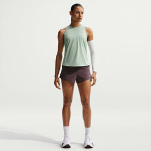 Woman wearing a light green sleeveless top and purple shorts on a white background