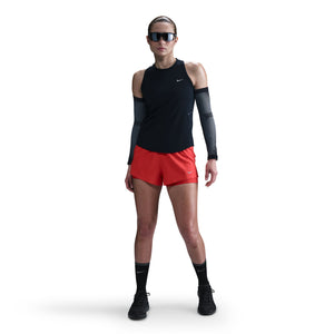 Person wearing a black sleeveless top, red shorts, and black shoes on a white background