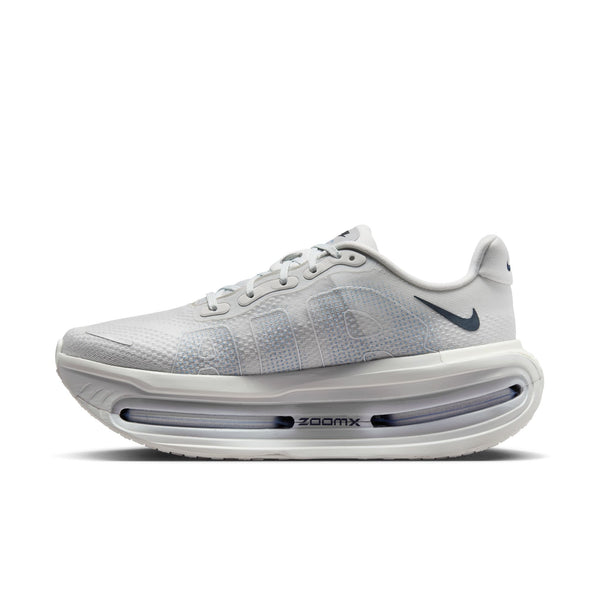 The medial side of a light grey nike shoe with a small swoosh near the heel.