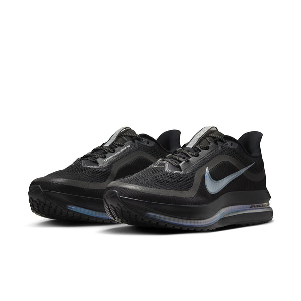 A pair of men's Nike shoes that are almost all black except for the swhoosh and the air zoom pods surrounding the midsole.