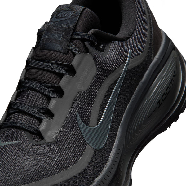 Black athletic shoe with close up on the Nike logo on a white background.
