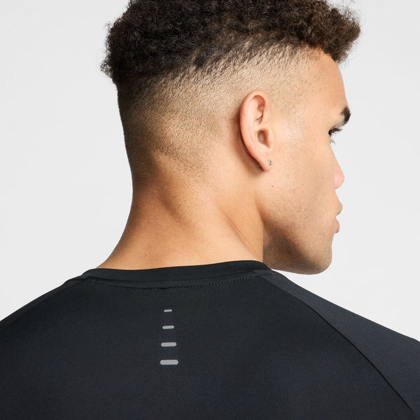 Person wearing a black athletic shirt with a subtle design on the back against a light gray background