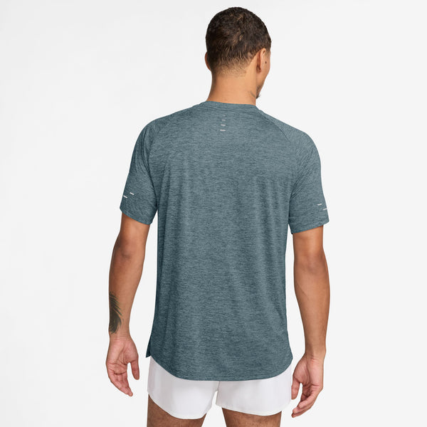 Man wearing a teal athletic shirt and white shorts on a white background