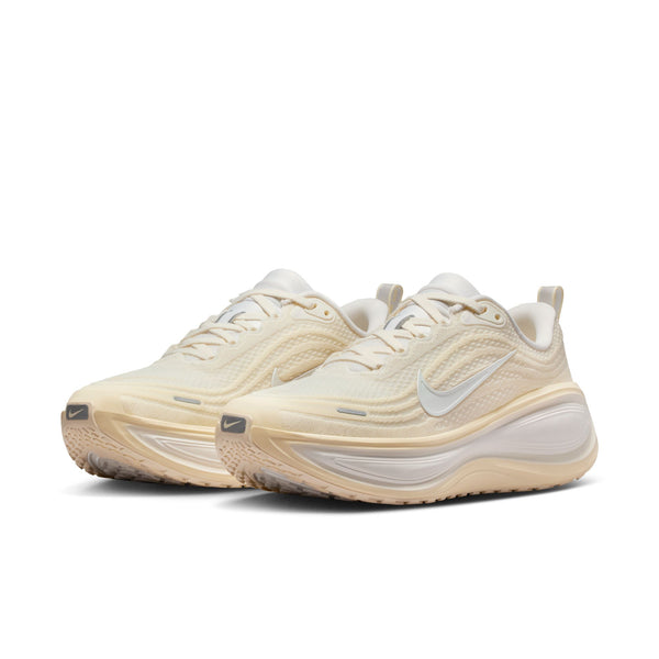 Pair of beige running shoes with a white Nike logo on a white background