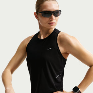 Woman wearing a black Nike tank top and sunglasses on a light gray background