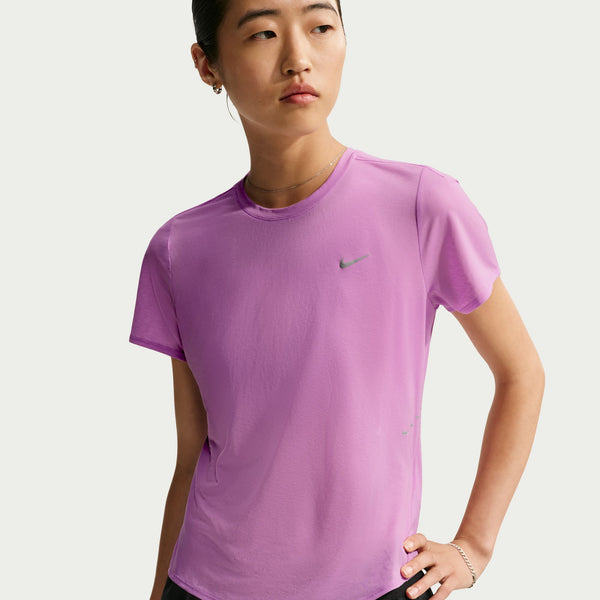 A woman wearing a light purple Nike athletic t-shirt with a small green swoosh logo on the chest, photographed against a light gray studio background.