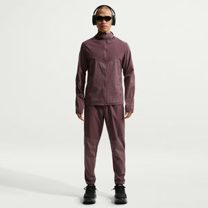 Person wearing a maroon jacket and pants with black shoes on a white background