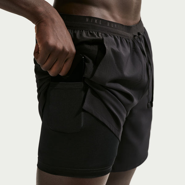 Person wearing black Nike shorts on a plain background