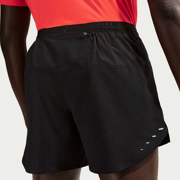Black athletic shorts worn by a person with a red shirt on a light gray background