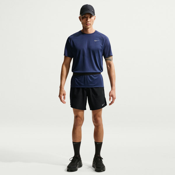 Man wearing a navy blue Nike t-shirt and black shorts on a light gray background