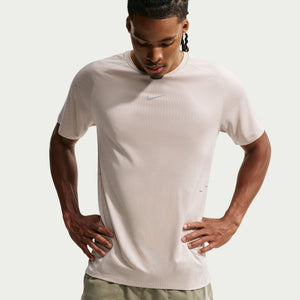 Man wearing a beige Nike t-shirt on a light gray background
