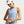 A woman wearing a light blue Nike athletic tank top, a white Nike visor, and a smartwatch, shown from the waist up against a light gray studio background.