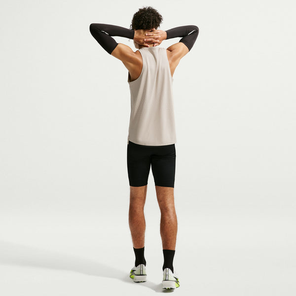 Person wearing a white tank top and black shorts on a light gray background