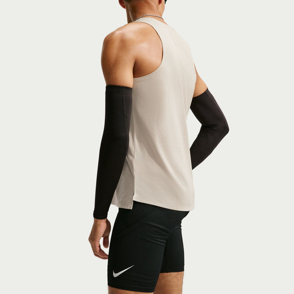 Person wearing a beige tank top and black shorts with a Nike logo on a light gray background