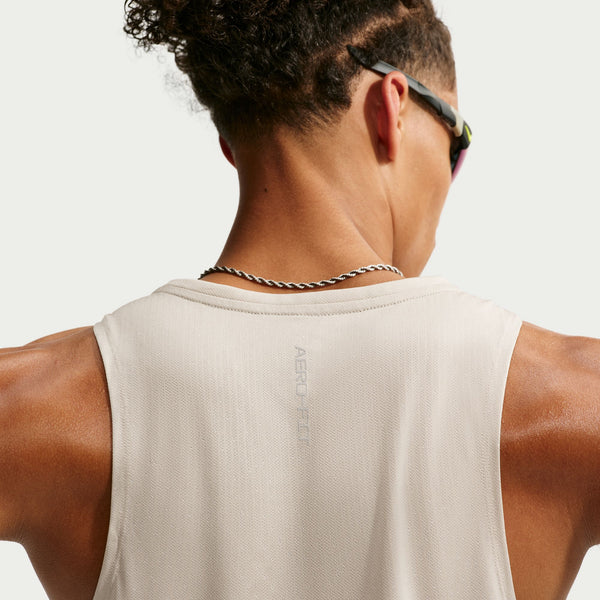 Person wearing a beige tank top with a brand logo on a white background